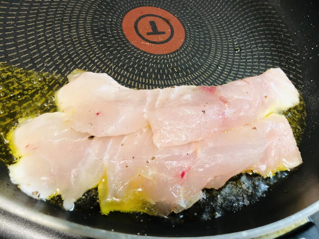 オリーブオイルを入れて温めたフライパンに塩コショウ↓真鯛の切り身を皮目から焼く様子の画像です
