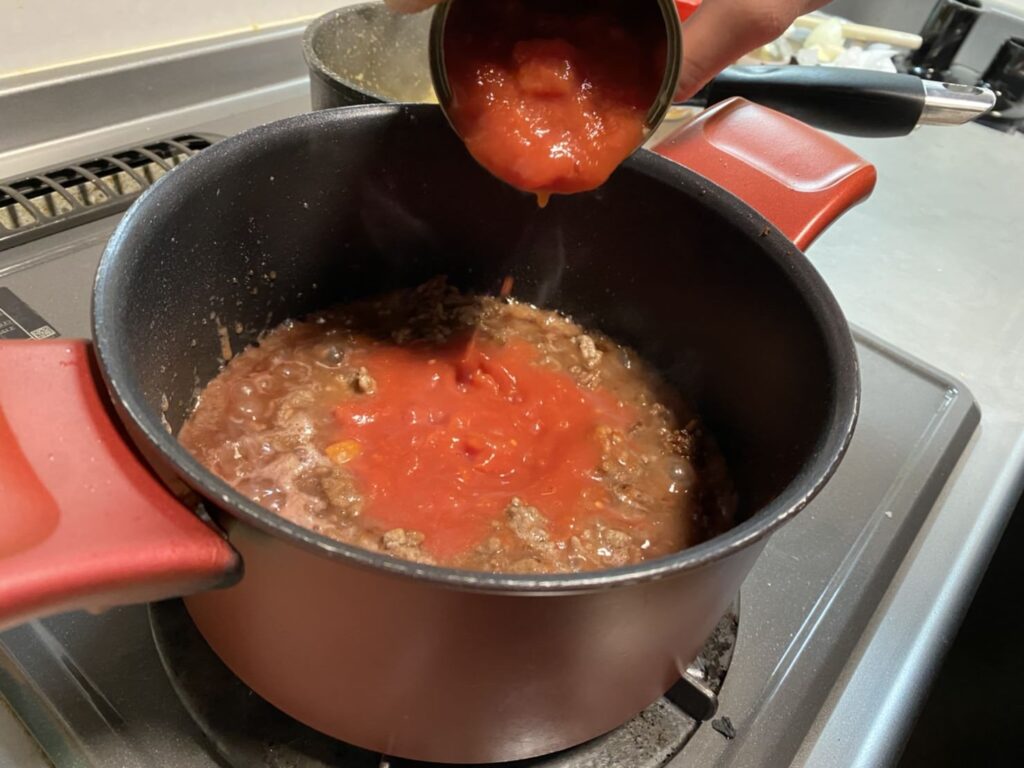 ボロネーゼを作る工程でトマト缶を入れる様子の画像です