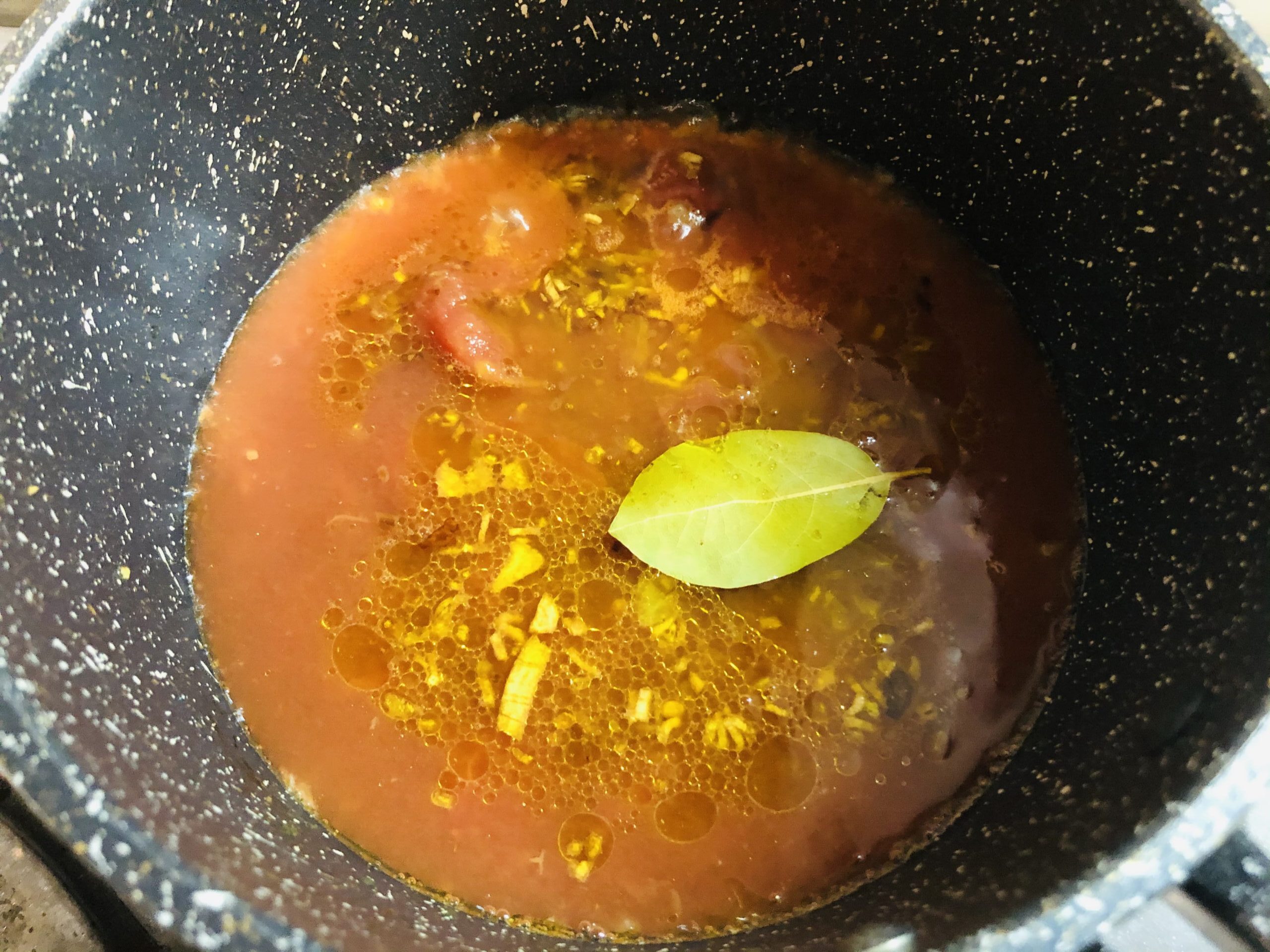 小鍋にトマト缶を入れてハーブ類を入れた画像です