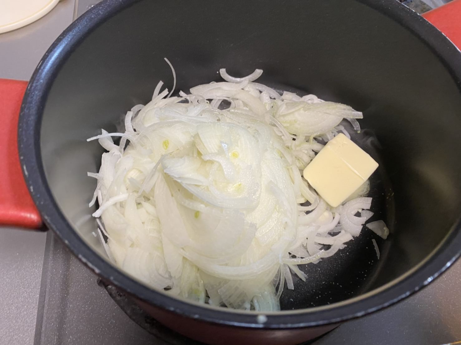 鍋にスライス玉ねぎとバター、塩を入れて火にかける様子の画像です。