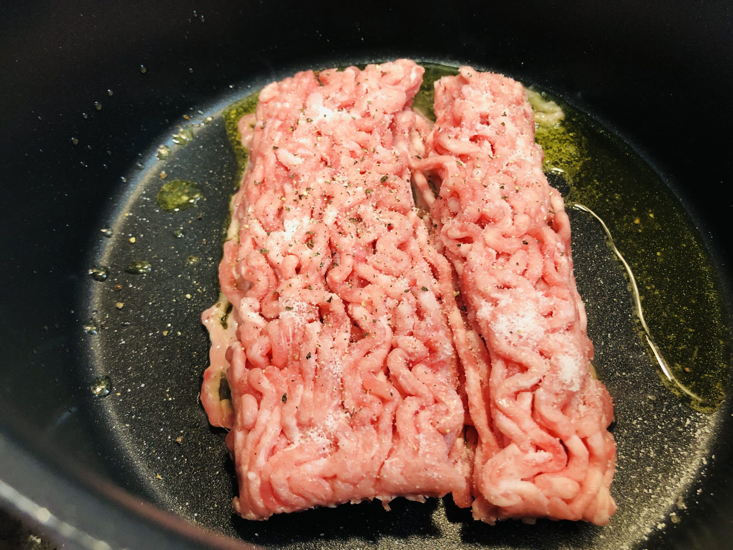 テフロン加工の鍋にオリーブオイルを引いてひき肉を入れ、塩コショウした状態の画像です