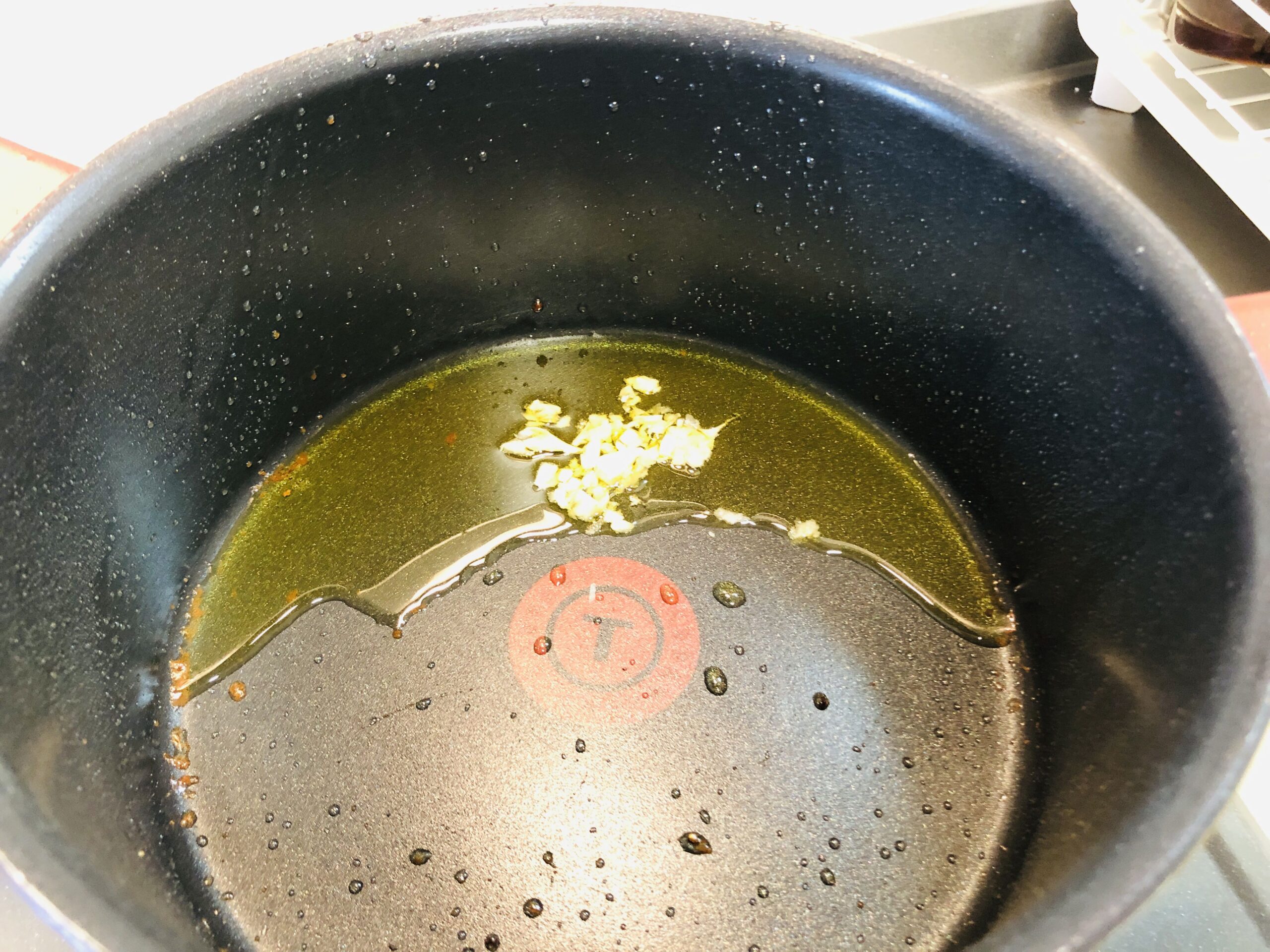 ミンチ肉を焼いた鍋にニンニクのみじん切りを入れた状態の画像です