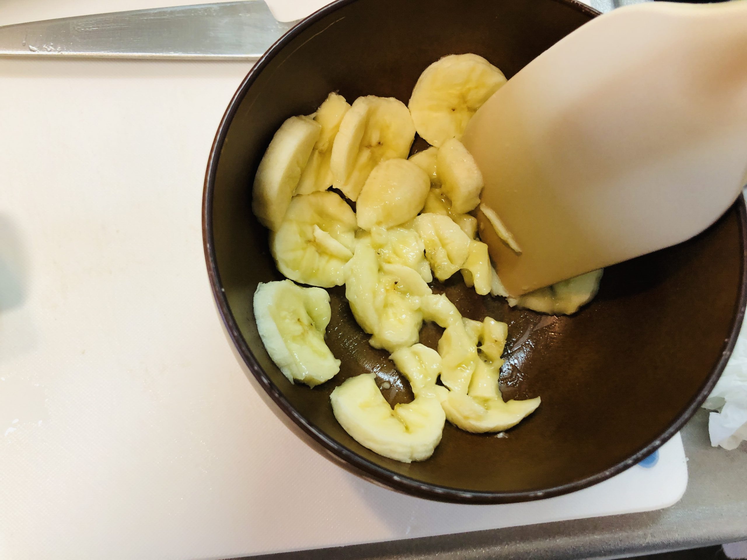 器の中でスライスしたバナナをゴムベラで潰している様子の画像です