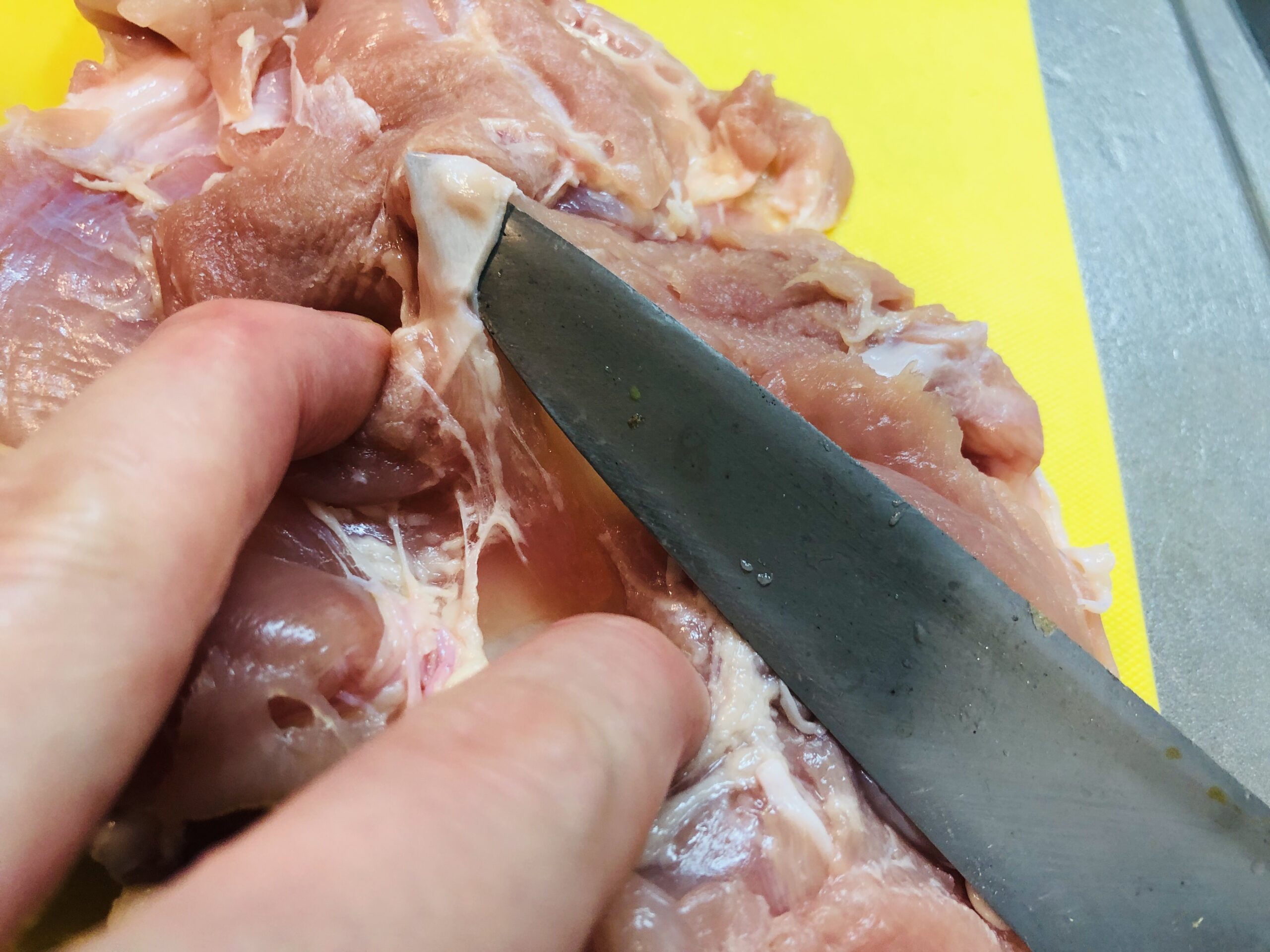 鶏もも肉の気になる筋を取り除こうとして包丁を入れている様子の画像です