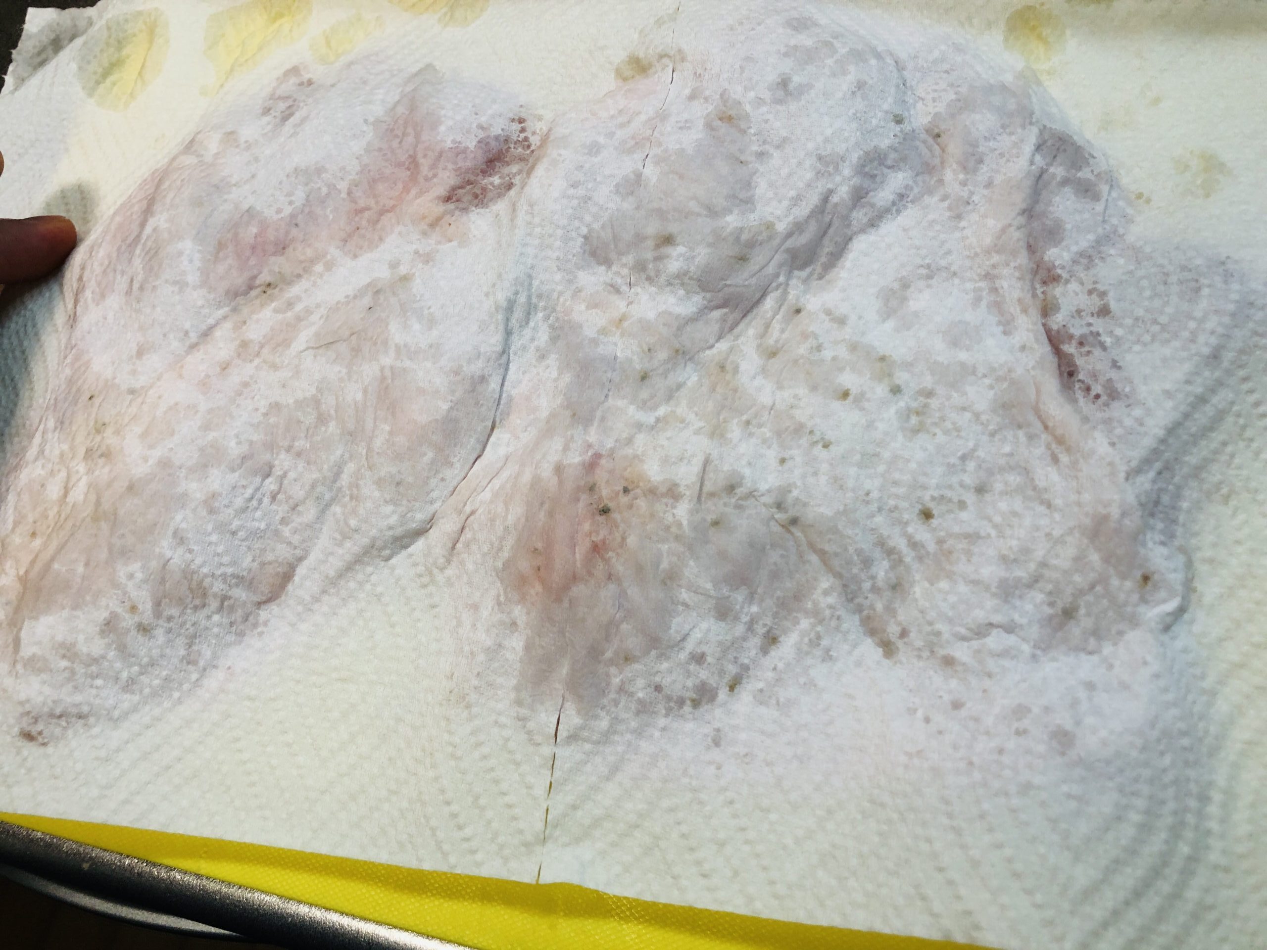 鶏もも肉に塩をして、２−３分おいて、出てき他水分を切ってインペーパーで拭き取る様子の画像です