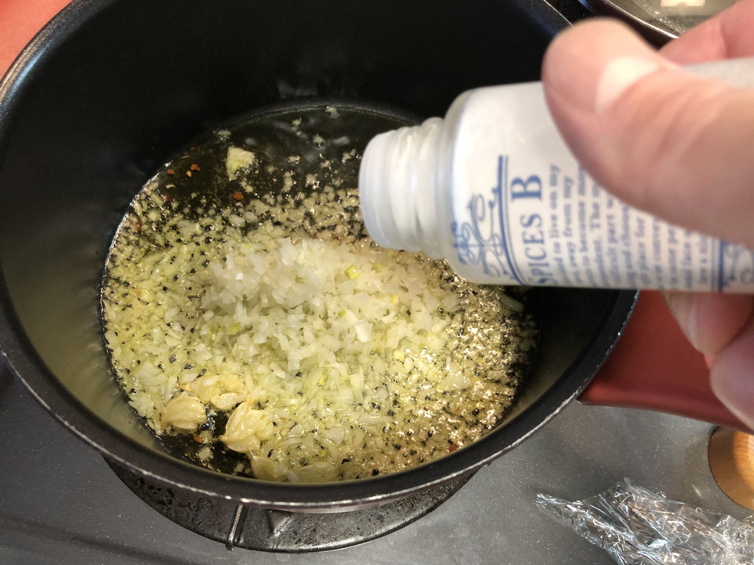 ニンニクの香りが出てきたので玉ねぎみじん切りと塩を軽く入れる様子の画像です