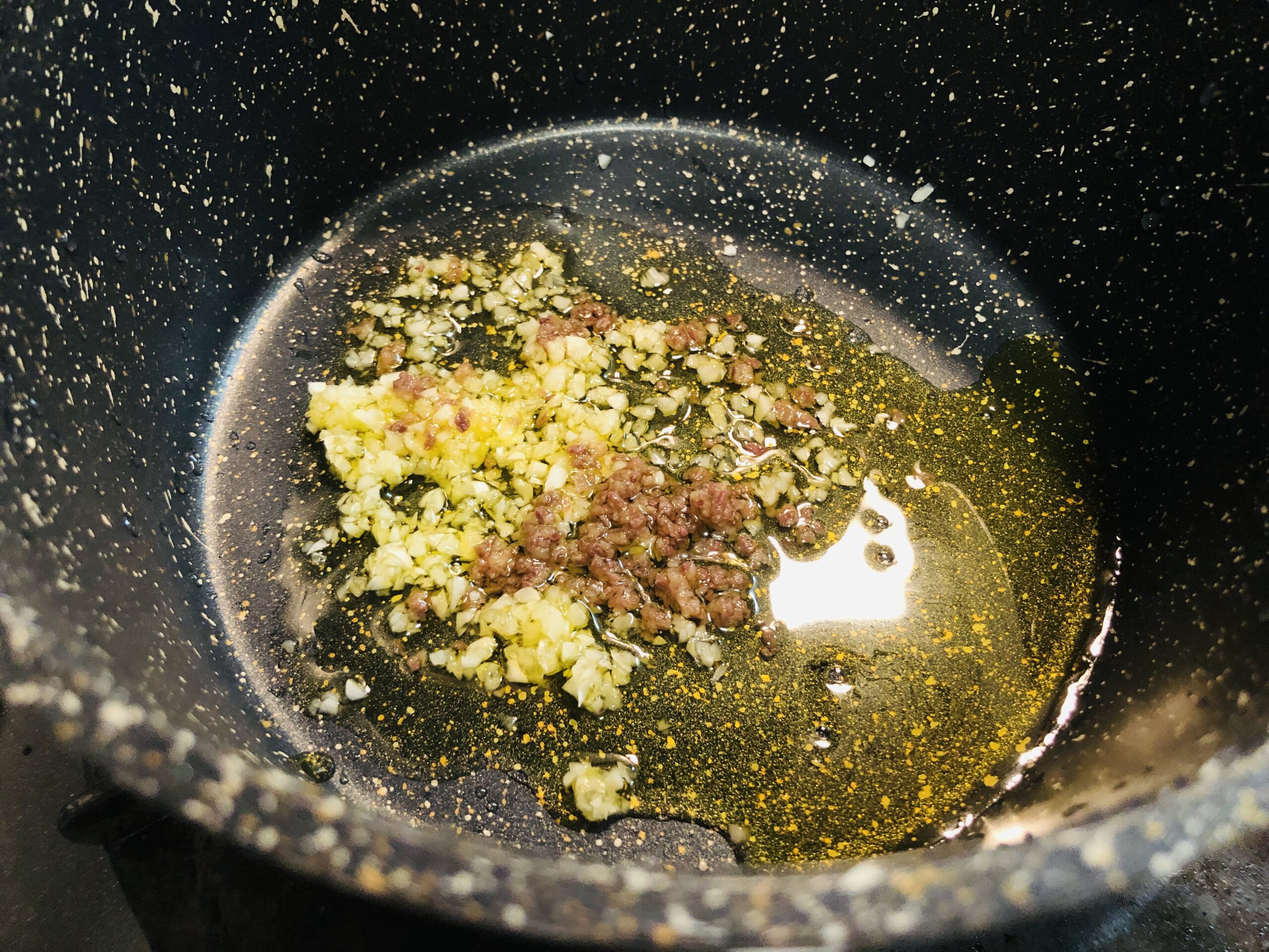 小鍋にオリーブオイル、ニンニクとアンチョビのみじん切りを入れた状態の画像です