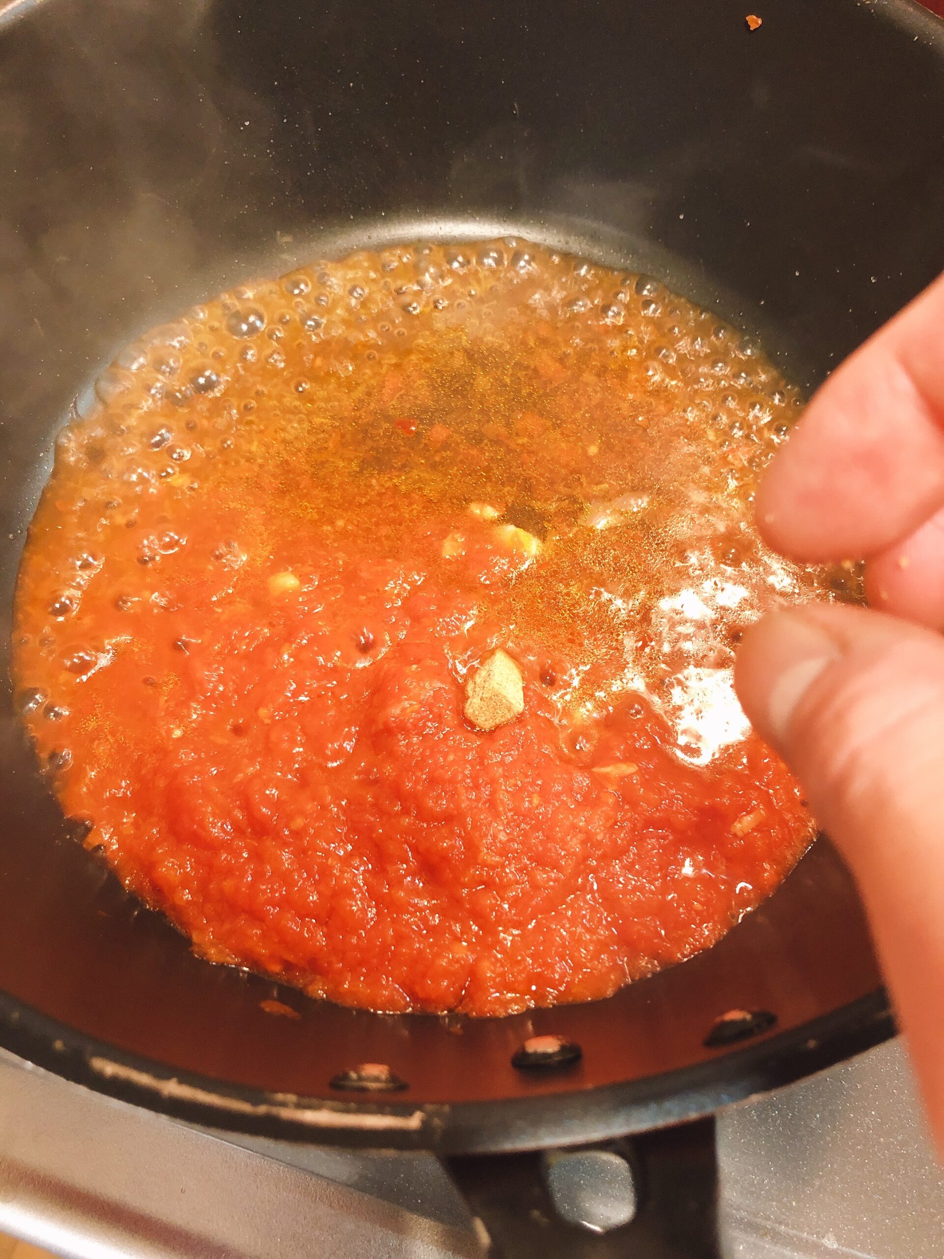 フライパンにトマトソースとパスタ茹で汁と固形コンソメ少量を加えた状態の画像です