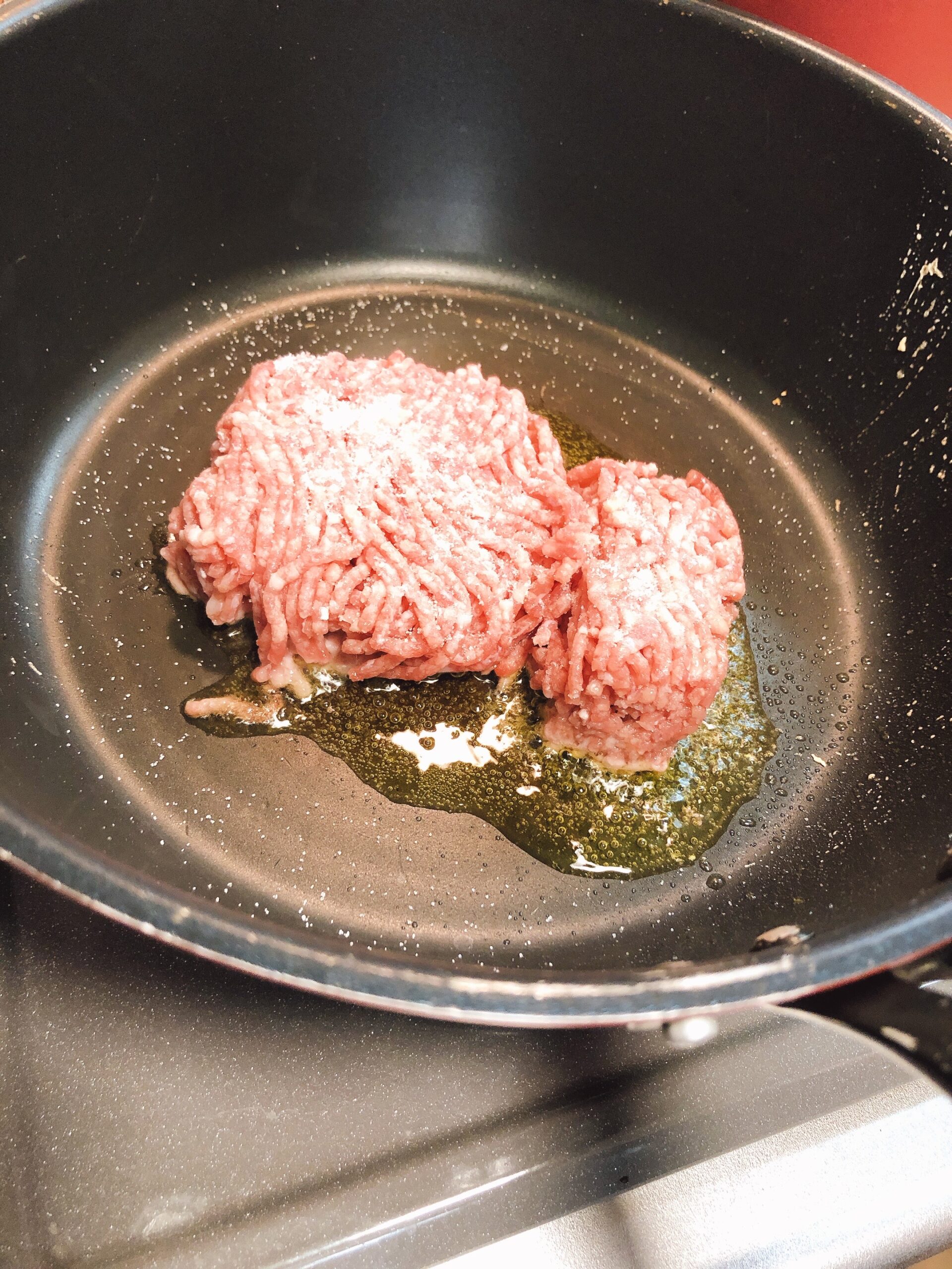 フライパンにオリーブオイルを入れてミンチ肉を加え、塩こしょうした状態の画像です