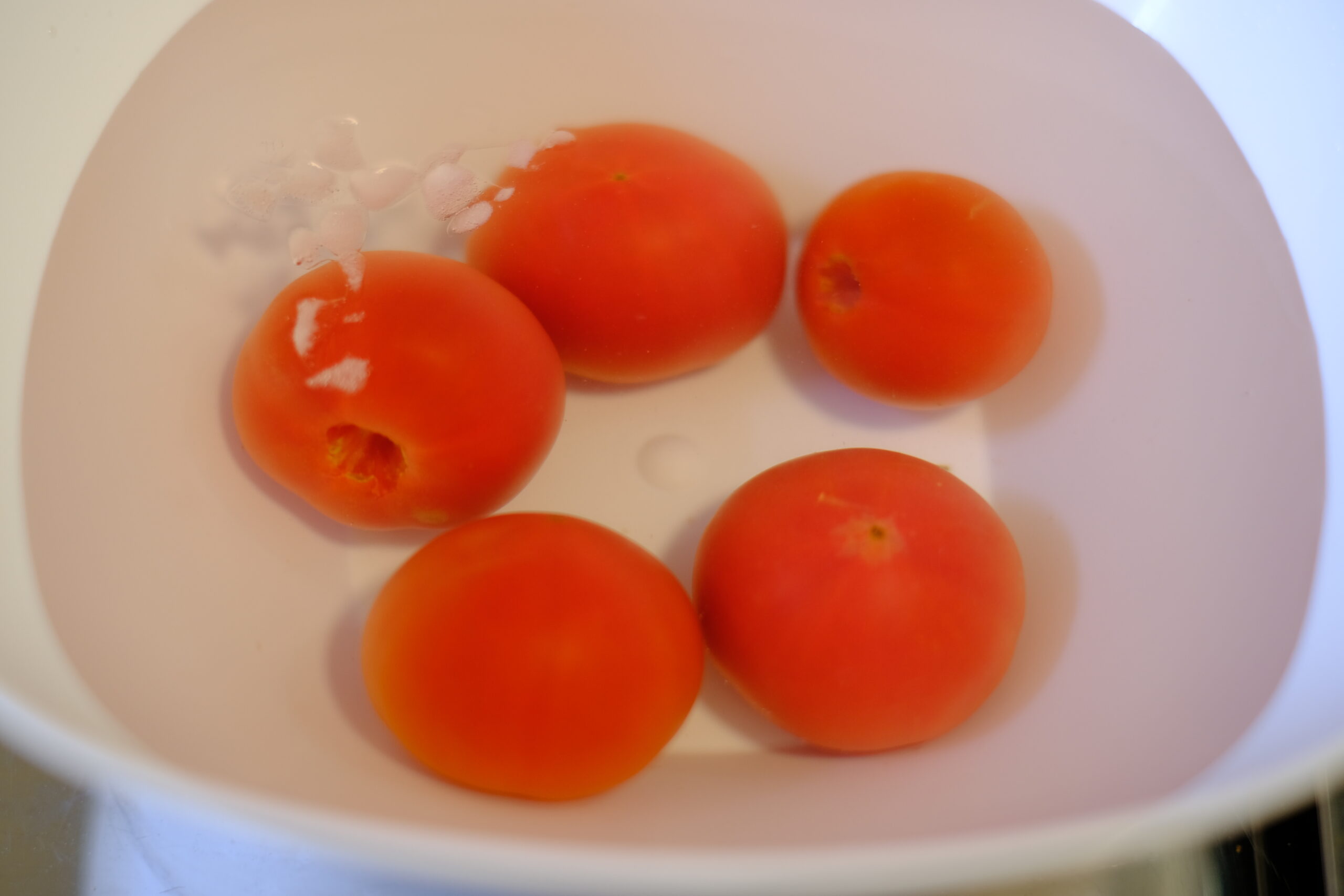 氷水を貯めたボウルにサッとお湯にくぐらせたトマトを沈めた状態の画像です