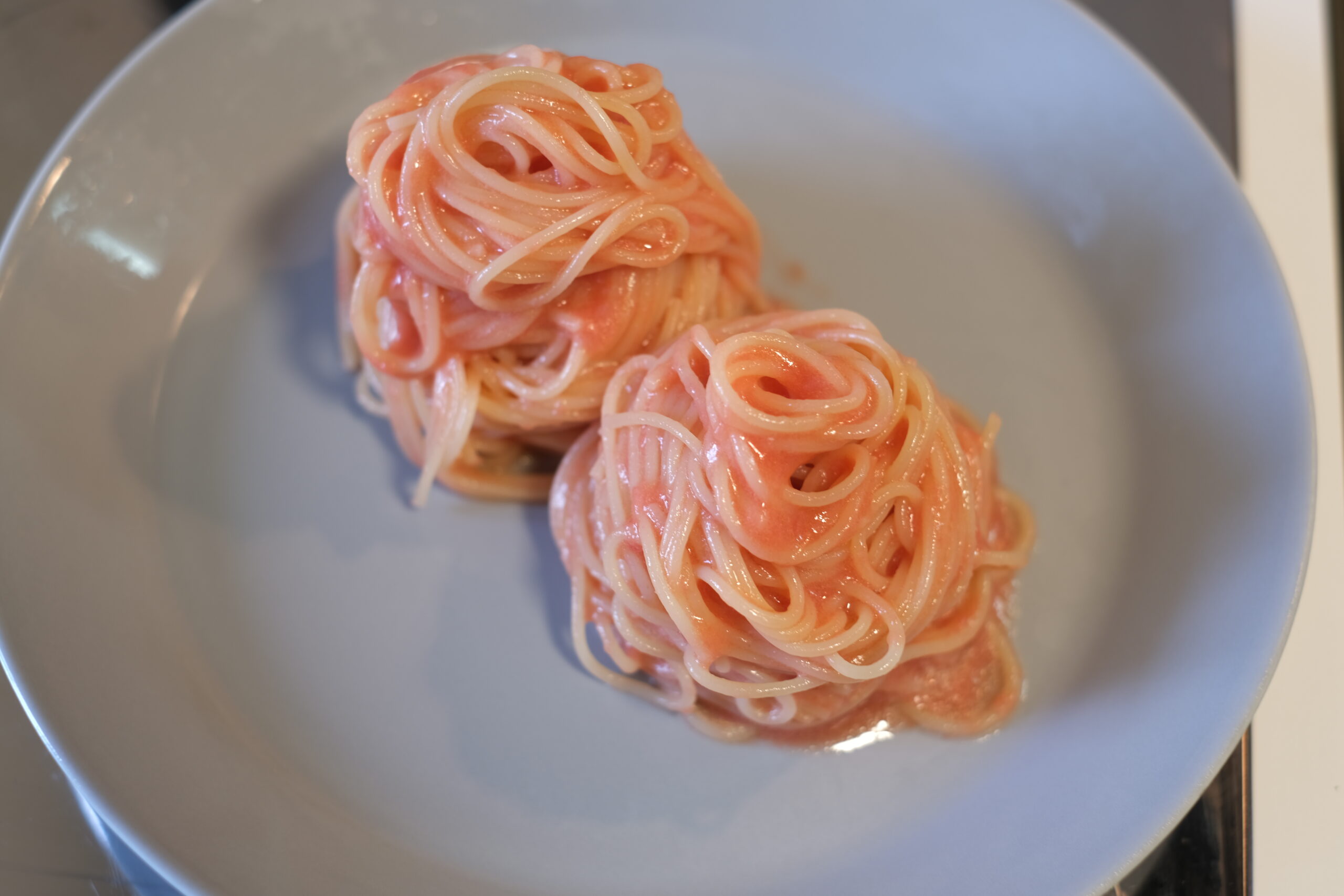 フルーツトマトソースを絡めたカペリーニをお皿に盛り付けた画像