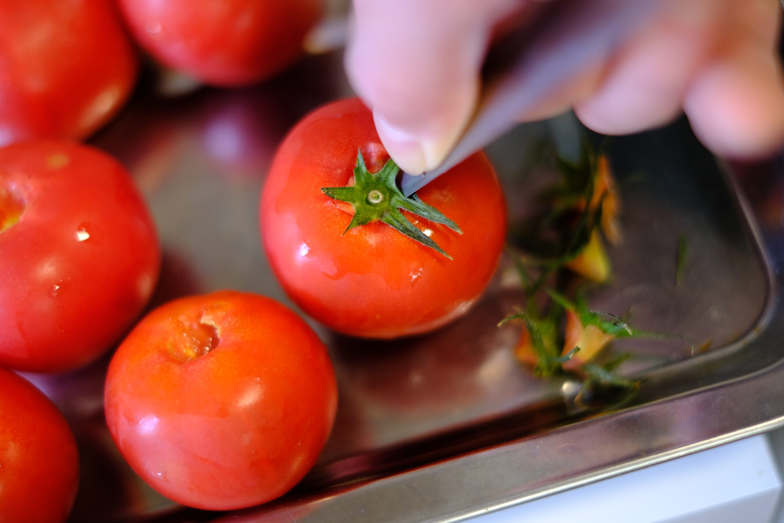 ペティーナイフを使ってフルーツトマトのヘタと芯を取り除く様子の画像です
