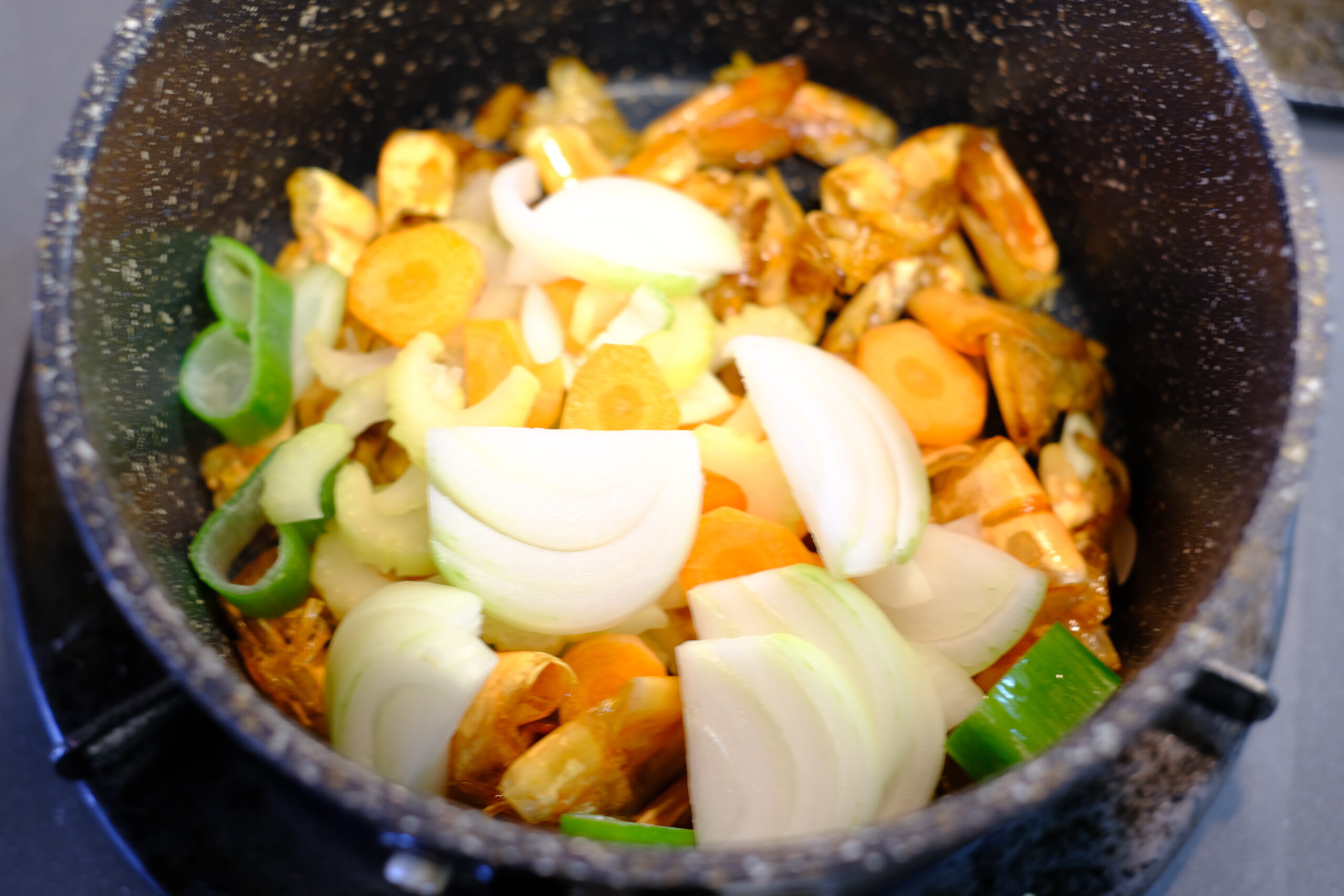 海老のソースを作る鍋に潰したニンニクとスライスした野菜を加えた画像です
