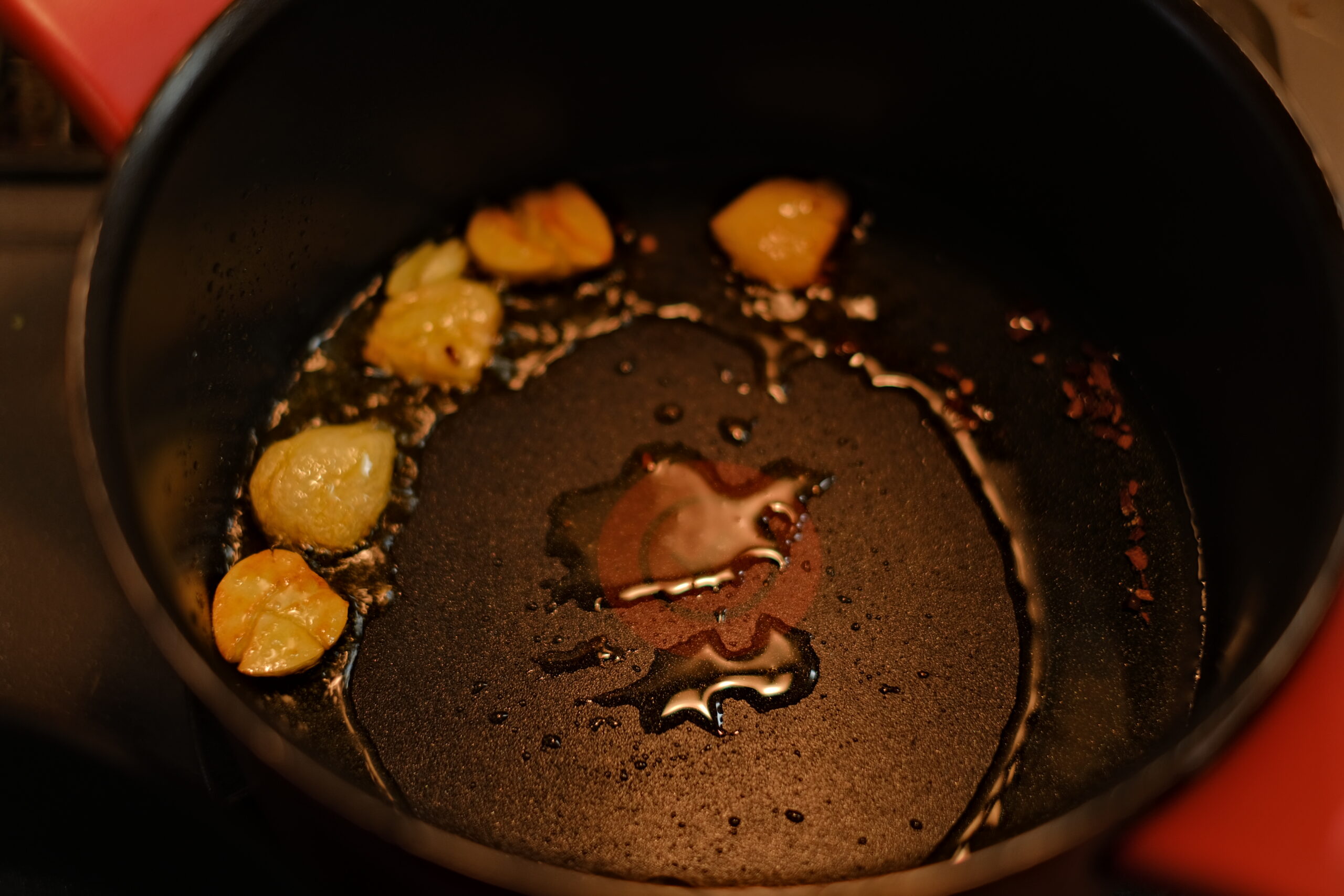潰したニンニクをオリーブオイルとともに弱火で香ばしく炒めている様子の画像です