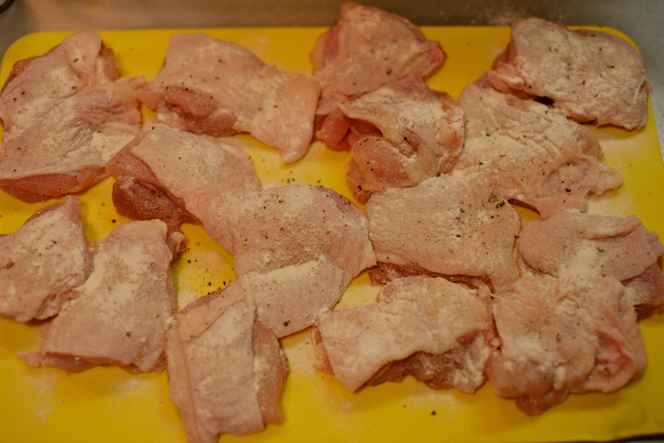 4〜6等分にカットして塩、こしょう、薄力粉をまぶした状態の鶏もも肉の画像