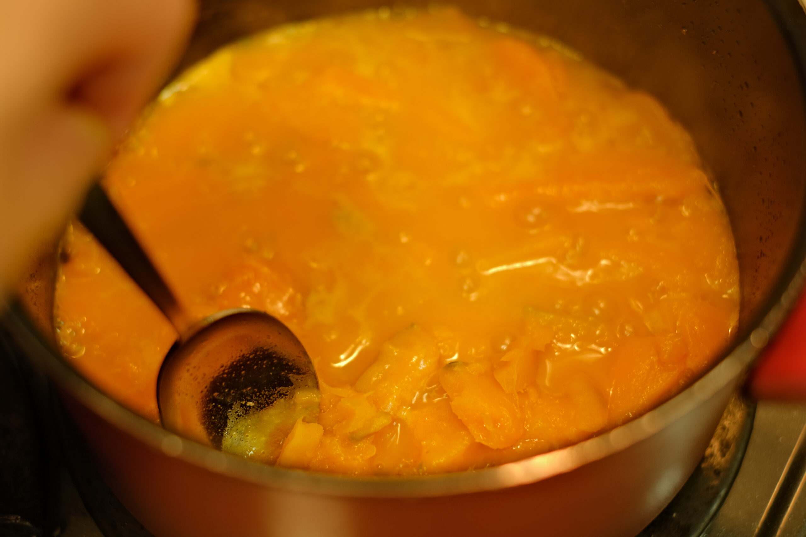 １５分ほど煮込んで柔らかくなったかぼちゃの硬さをスプーンで確かめている様子の画像です